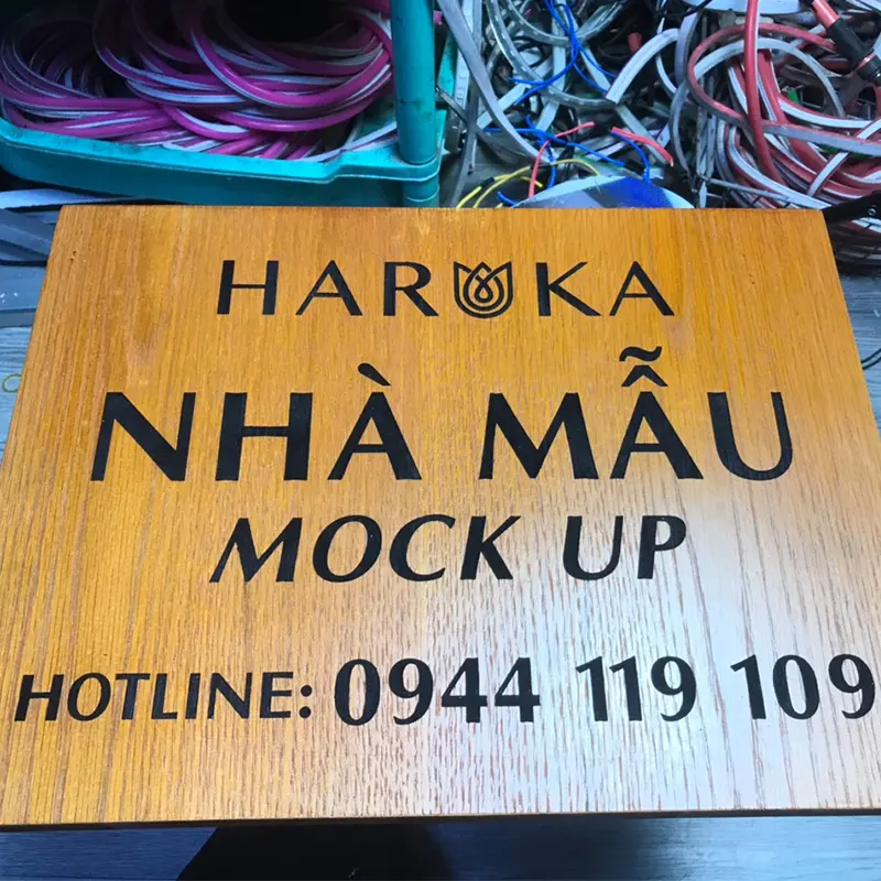 Bảng hiệu gỗ Nhà Mẫu Mock Up, thiết kế hiện đại trên nền gỗ tự nhiên, chữ in nổi bật và sắc nét.
