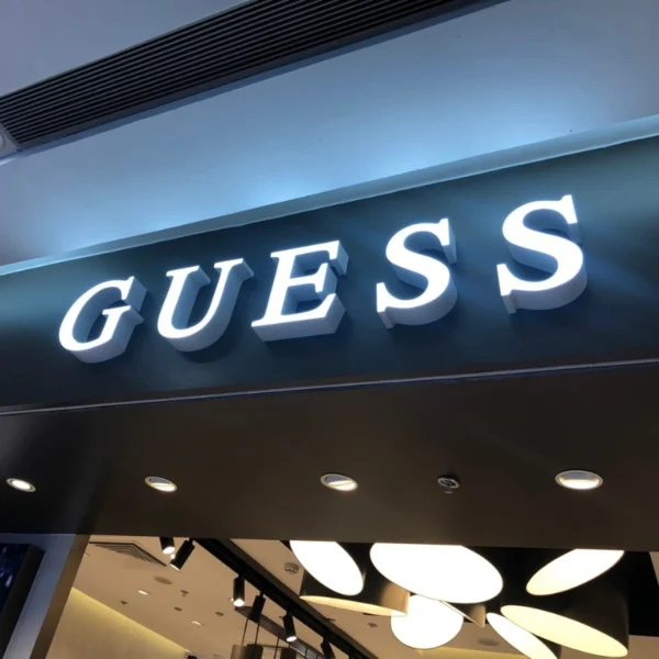 Chữ nổi mica trắng thương hiệu GUESS gắn trên nền đen, có ánh sáng LED nổi bật